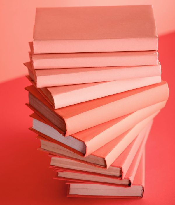 pile of books on living coral background. Pantone color of the year 2019 concept