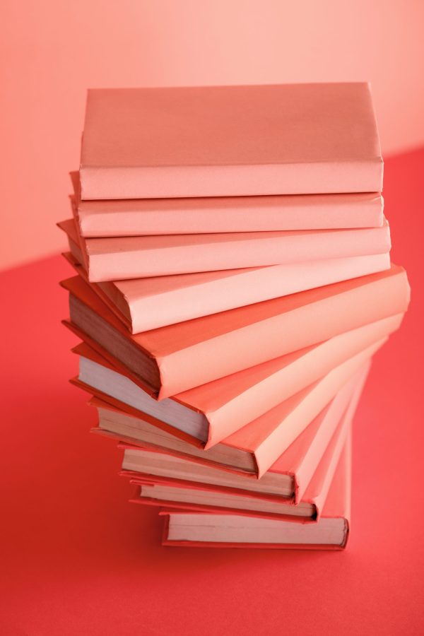pile of books on living coral background. Pantone color of the year 2019 concept